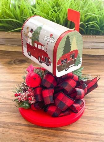 petite boîte aux lettres peinte avec des photos d'un camion rouge avec un bonhomme de neige et un arbre à l'arrière et un poteau de remorque de style années 50 et le fond est entouré d'un ruban à carreaux noir et rouge et de houx et cardinal artificiels
