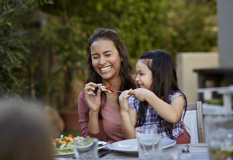 fille essayant de nourrir sa mère à l'extérieur du dîner, en riant