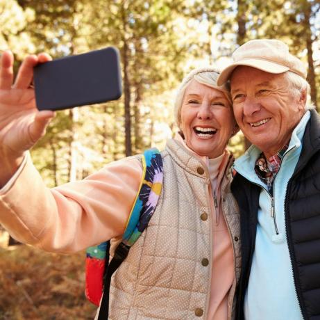 Couple de personnes âgées en randonnée dans une forêt prenant un selfie