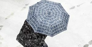 Vue grand angle de la personne avec un parapluie marchant dans la neige dans la rue avec un parapluie rouge dans la tempête de neige. Valence, Espagne