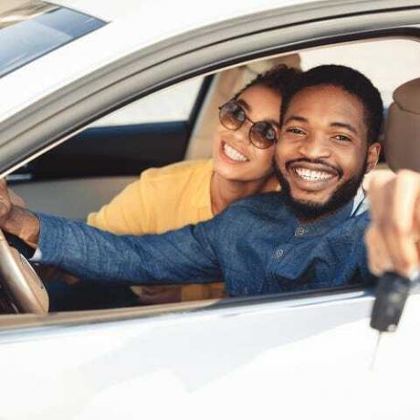 conjoints afro-américains montrant une nouvelle clé de voiture assis dans une automobile