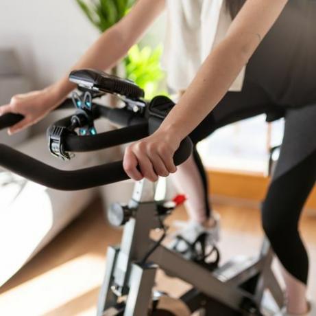 Low section shot of a woman in sportswear exerçant sur un vélo d'exercice à la maison