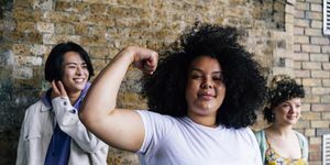 jeune femme flexing muscle avec des amis masculins et féminins en arrière-plan