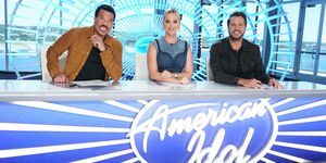 lionel richie, katy perry et luke bryan assis à un bureau avec le logo de l'idole américaine sur le devant