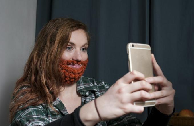 femme portant une barbe au crochet rouge prenant un selfie pour la saint patrick