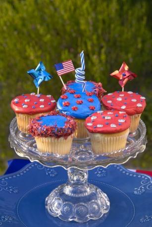 six petits gâteaux décorés en rouge ou bleu sur un support à gâteaux en verre taillé