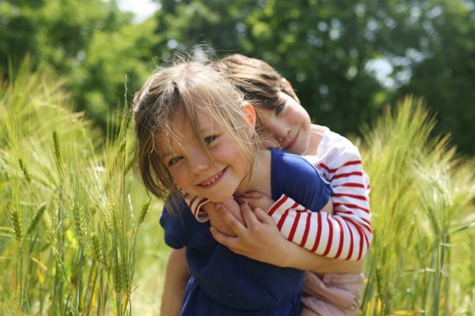 une fille portant son petit frère dans un champ de blé