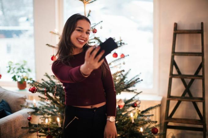femme prenant un selfie devant un arbre de Noël