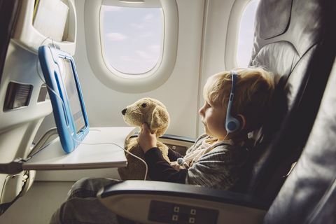 Petit garçon assis sur un avion en regardant quelque chose sur une tablette numérique