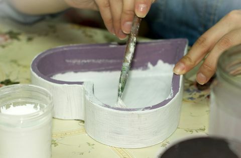 Mains peignant l'intérieur d'une boîte en forme de coeur en bois violet blanc