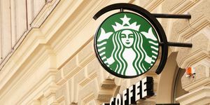 vienne, autriche 1er mai 2012 logo vert du café starbucks sur un poteau et texte du café starbucks sur la façade de Une vieille maison dans le centre de Vienne photographiée en diagonale, l'accent sur le logo Starbucks est connu pour ses grands déplacements café