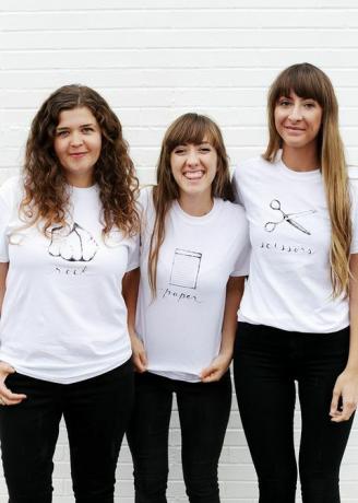 trois femmes en t-shirts blancs, avec des pierres, du papier ou des ciseaux écrits et représentés sur le t-shirt