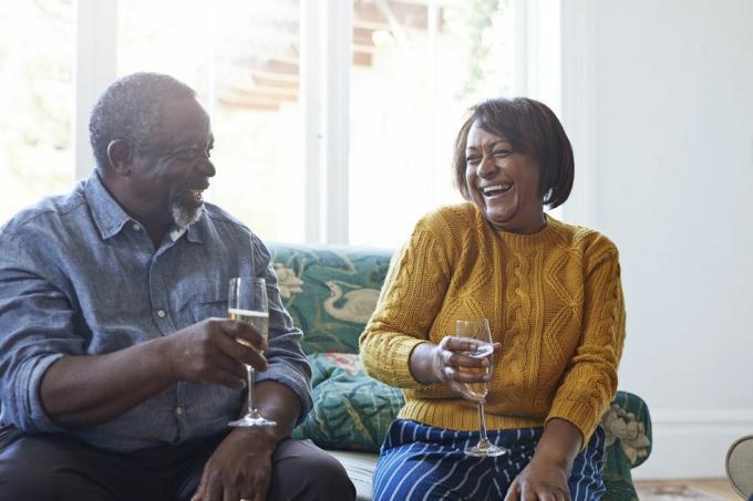 joyeux amis masculins et féminins appréciant le champagne tout en parlant à la maison pendant la fête de noël