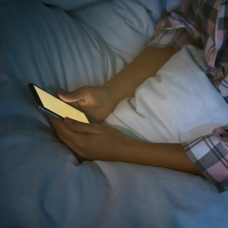 femme utilisant un smartphone au lit la nuit, gros plan sur la nomophobie et le problème des troubles du sommeil