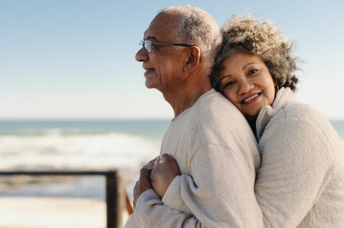 femme senior romantique souriant à la caméra tout en embrassant son mari au bord de l'océan couple de personnes âgées affectueux appréciant passer du temps de qualité ensemble après la retraite