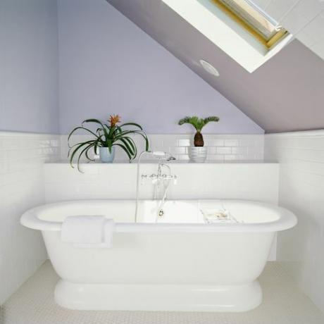 baignoire sous lucarne dans une salle de bains mansardée aux murs violet lilas