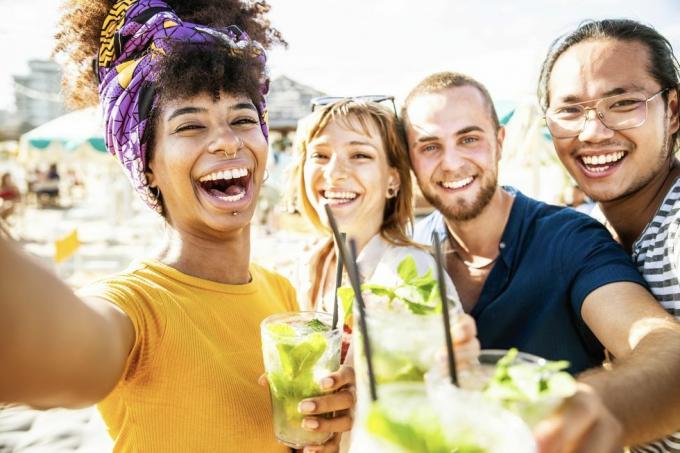 amis multiraciaux acclamant des cocktails à la fête sur la plage jeunes gens riant ensemble s'amusant pendant les vacances d'été concept d'amitié avec des gars et des filles souriant dehors pendant les vacances d'été