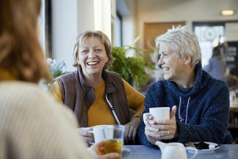 couple de lesbiennes et fille adulte buvant du café et parlant au café