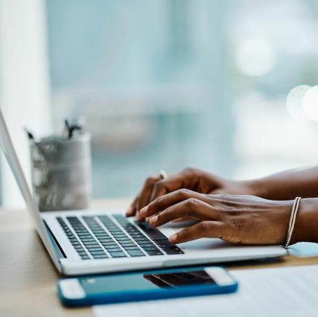 gros plan d'une femme d'affaires noire tapant sur le clavier d'un ordinateur portable dans un bureau seul