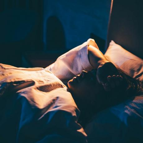 femme souffrant d'insomnie jeune femme allongée sur le lit avec la main sur le front