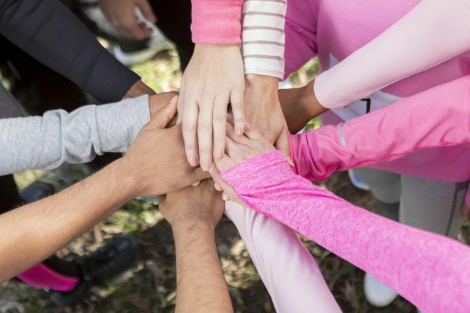 cercle de personnes portant des chemises roses, les mains jointes dans l'unité