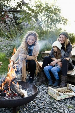 deux femmes et une fille assises près d'un foyer, relaxantes