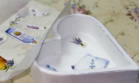 Boîte blanche en forme de cœur avec des images découpées de lavande au fond et d'autres découpes à côté