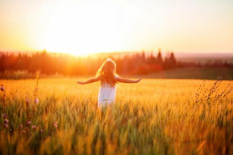 petite fille en robe blanche dans le champ au coucher du soleil