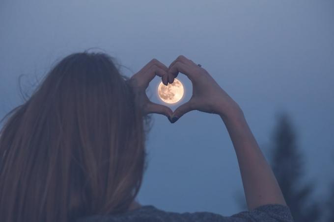 femme en forme de coeur avec ses mains sur la pleine lune