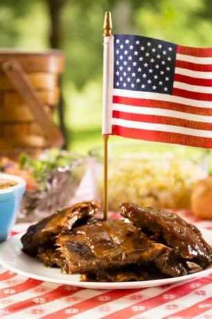 Côtes levées grillées au drapeau américain, haricots, salade de pommes de terre sur une nappe rouge et blanche