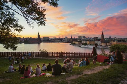 Personnes ayant pique-nique dans un parc avec panorama de Stockholm pendant le coucher du soleil, Suède