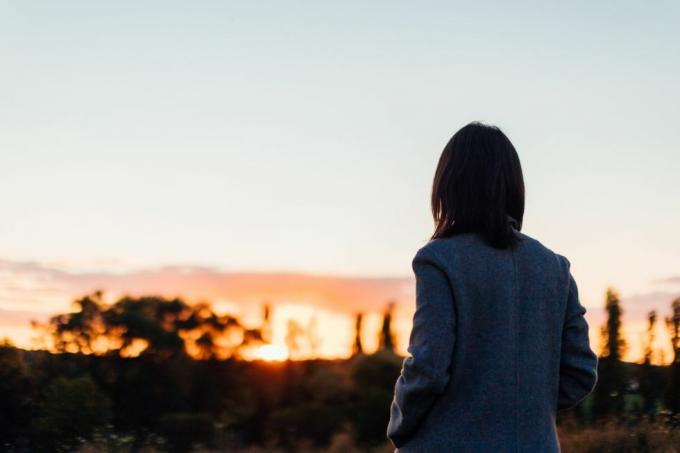 vue arrière d'une jeune femme déprimante regardant le coucher du soleil au parc auto-soins pour le concept de bien-être mental