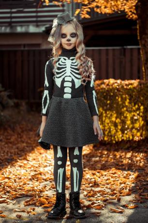 costume de squelette de bricolage sur un garçon dans un champ de citrouilles