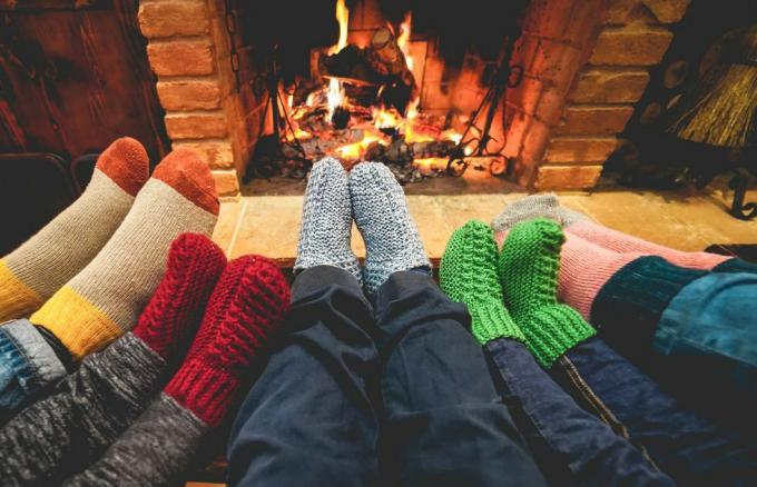 vue sur les jambes d'une famille heureuse portant des chaussettes chaudes devant la cheminée l'hiver, l'amour et le concept confortable se concentrent sur les chaussettes en laine grise centrale