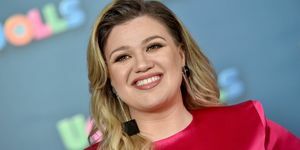 Kelly Clarkson sourit en robe rose et boucles d'oreilles noires carrées