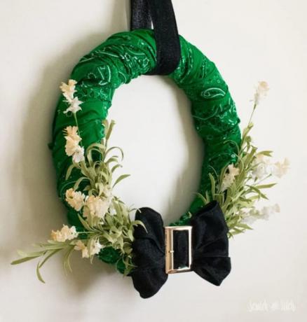 couronne verte faite de bandanas avec un nœud noir avec une boucle dorée en bas le faux feuillage feuillu sortant de l'arc